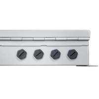 Close up of a hinged metal box with four black port holes on the side.