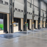 Multiple industrial garage doors with yellow swing arm dock lights in a warehouse setting.