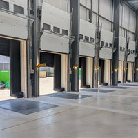 Multiple industrial garage doors with yellow swing arm dock lights in a warehouse setting.