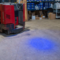 Blue safety light cast onto concrete floor from fork lift.