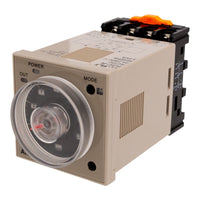 Front angled perspective of a tan industrial timer with black face and red needle. There is a black and orange adapter mounted to the rear of the timer on a white background.