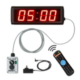 Digital clock with red LED display, power adapter, remote control, and wall plug on a white background.