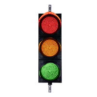 A 12 inch diameter lens LED traffic light with three lights in red, yellow, and green colors, mounted on a black housing with two steel right angle mounting brackets.