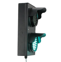 Angled perspective of a black four inch 2-light traffic light with green illuminated LEDs on a white background