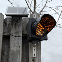 Amber solar powered 8 inch traffic light mounted outdoors.