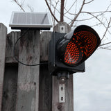 Red solar powered 8 inch traffic light mounted outdoors.
