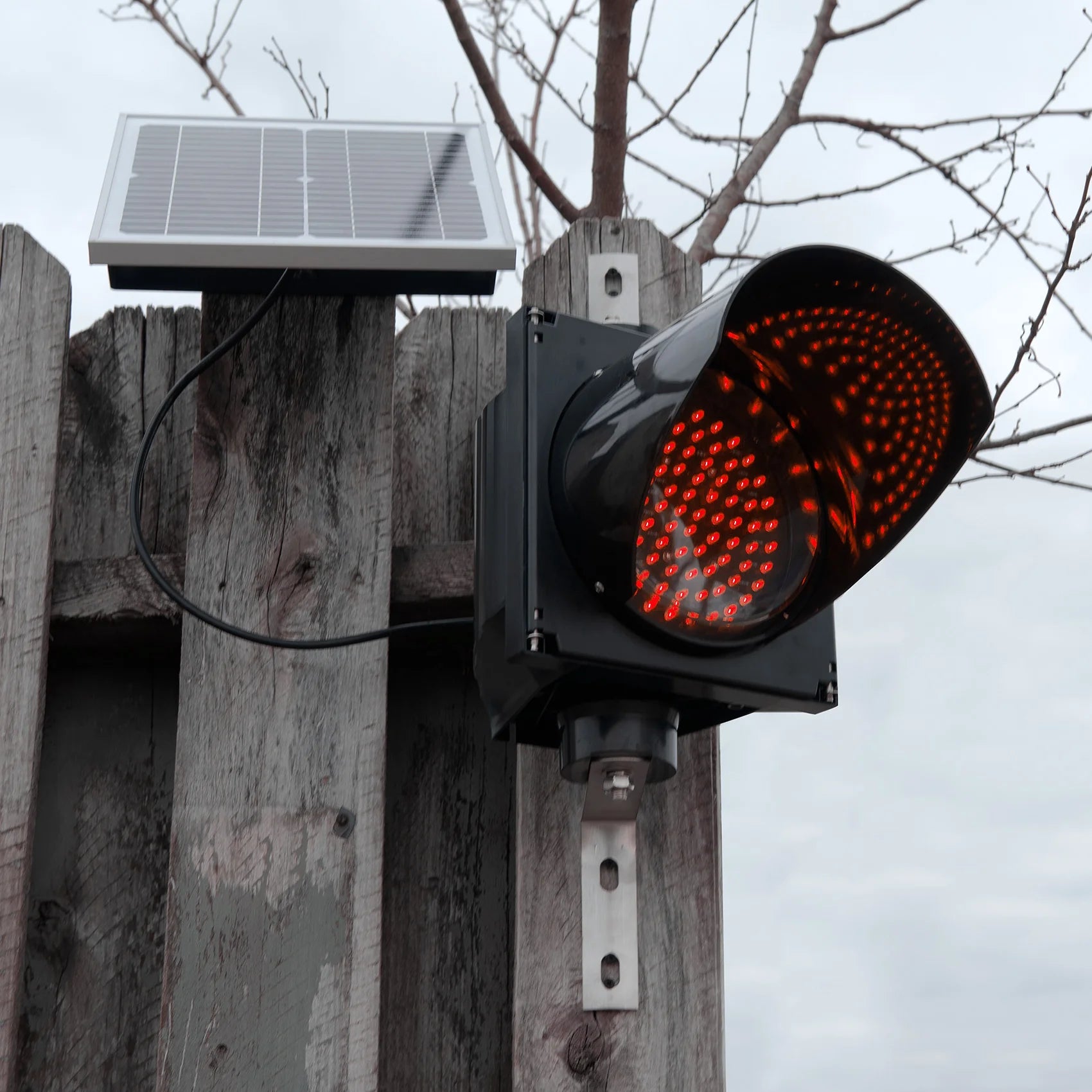 Red solar powered 8 inch traffic light mounted outdoors.